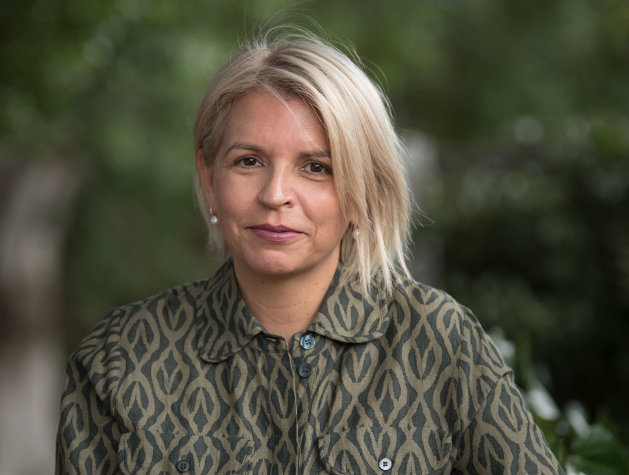 A photo of Kurin Minang woman Dr Hannah McGlade, standing in a park, looking at the camera, smiling slightly.