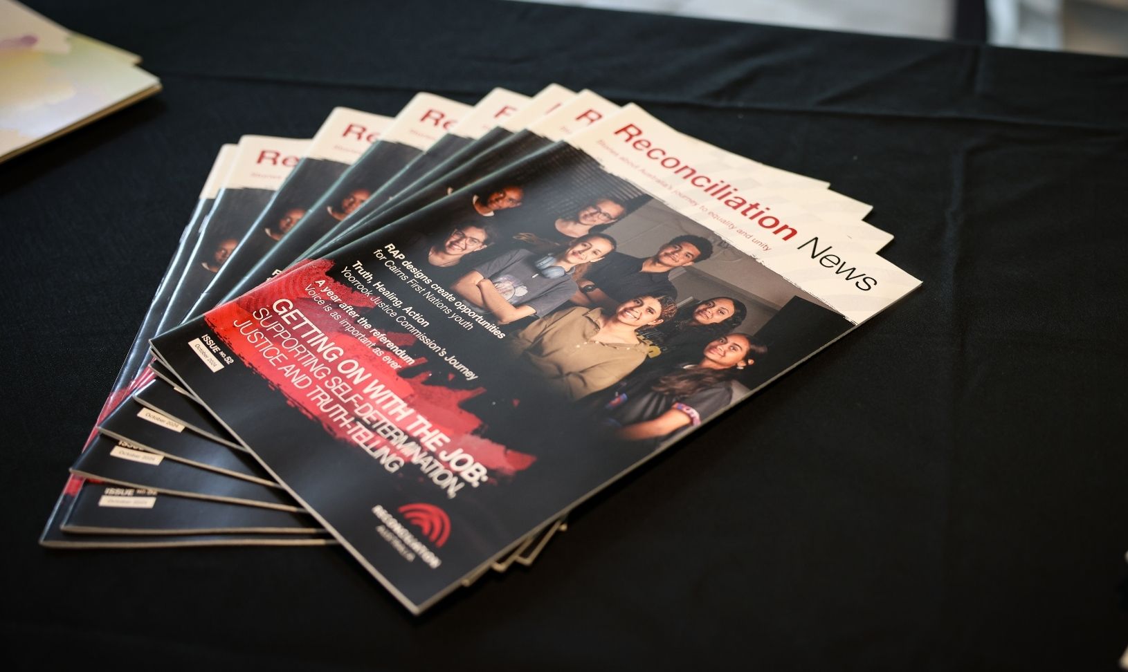 A stack of Reconciliation News magazines on a table