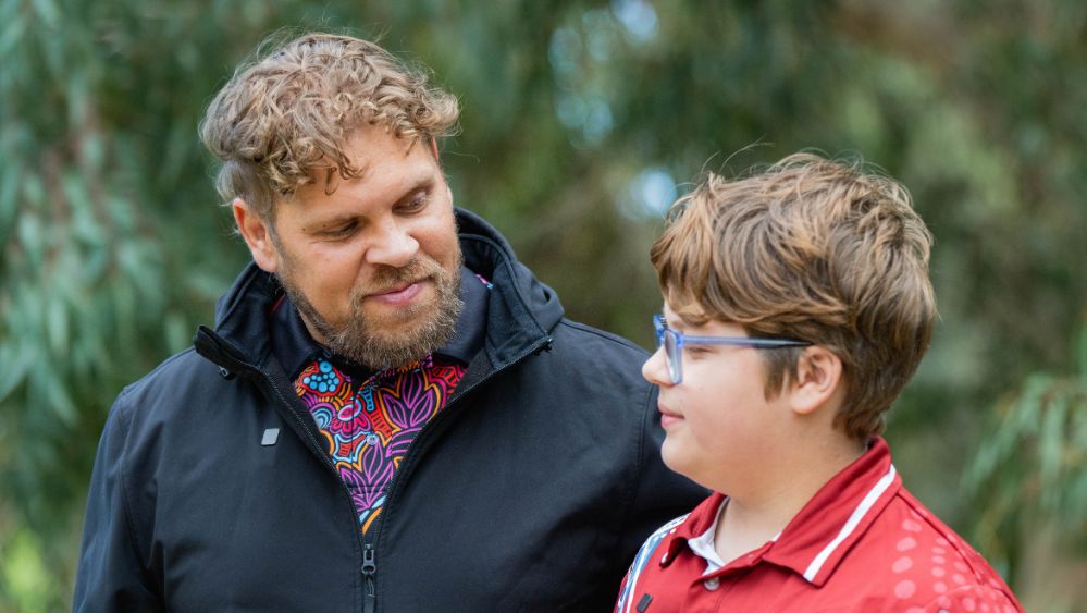 A father and son at the son's school, smiling at each other.