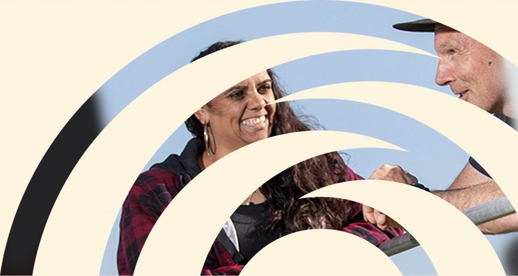 Two people, an Aboriginal woman and a non-Indigenous man, leaning on a farm fence.