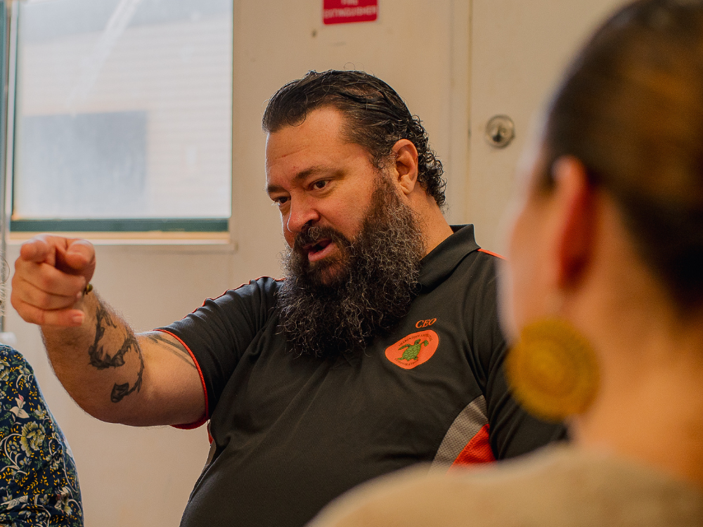 A man in a polo shirt that says 'CEO' on the pockets points at something off camera.